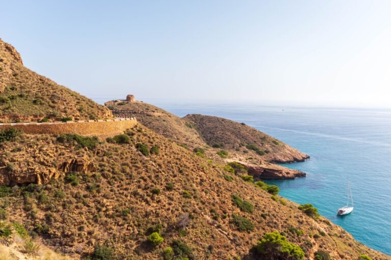 Boat is docked on the coast, with a majestic mountain range and a tranquil body of water in Benidorm